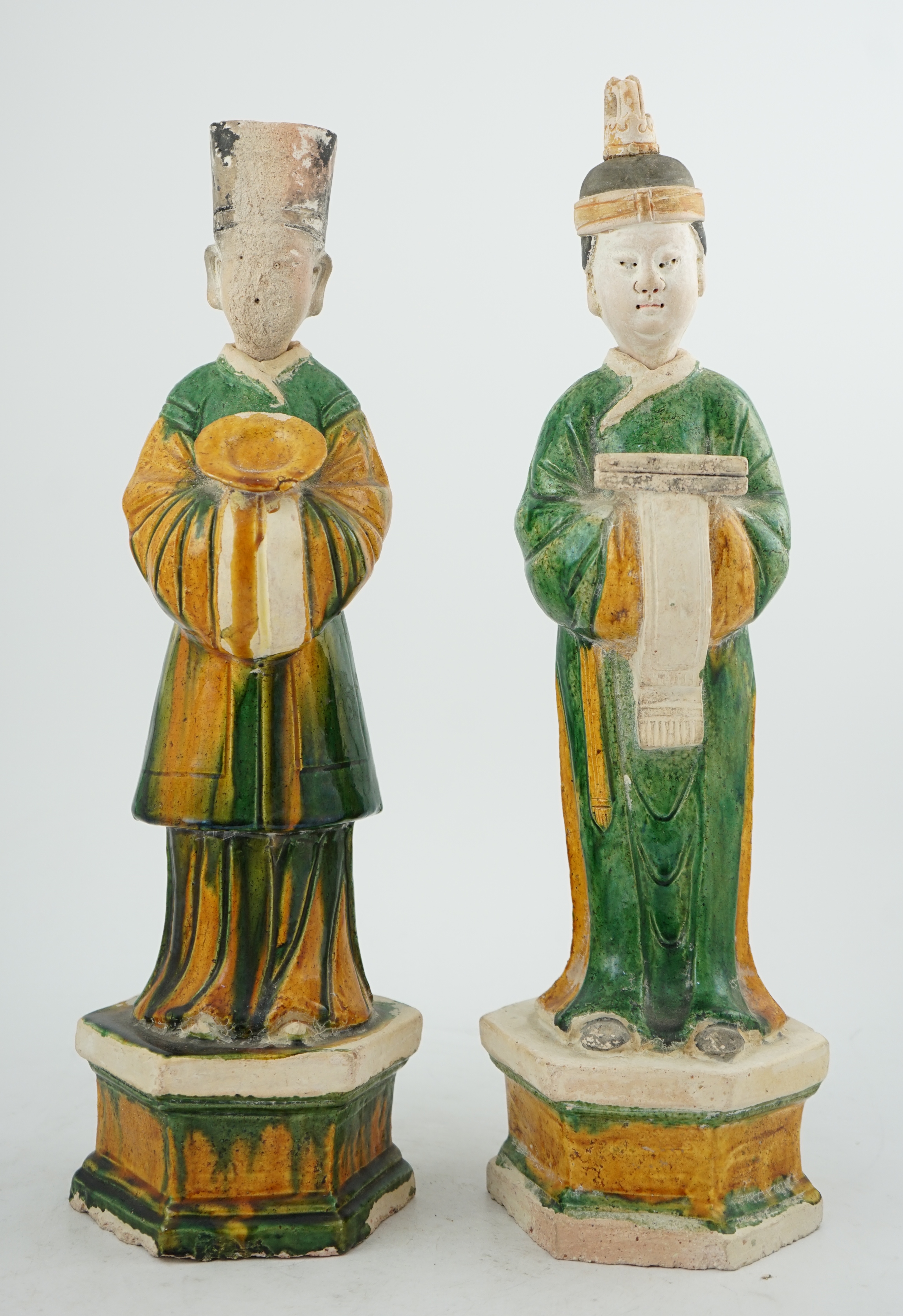 Two tall Chinese sancai figures of attendants, Ming dynasty, the male figure holding a dish and the female figure a box, each standing on a hexagonal base, largest 47cm high. Condition - some wear to face